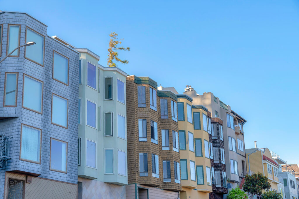 Row of colorful multifamily homes under a clear blue sky, representing passive income opportunities in real estate — featured in the article "The Power of Passive Income: Building a Cash Flow Real Estate Portfolio" and highlighting the keyword passive income.