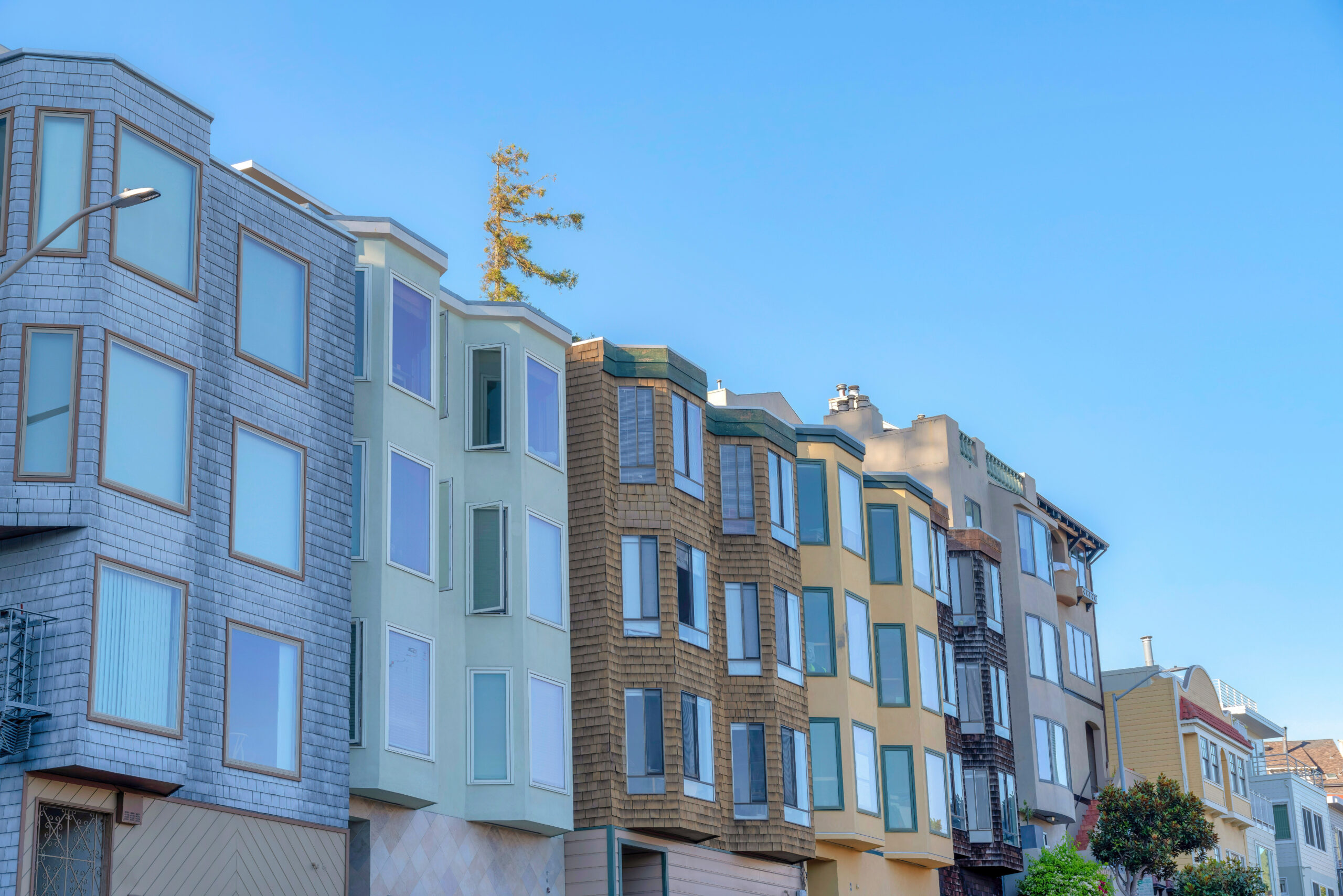 Row of colorful multifamily homes under a clear blue sky, representing passive income opportunities in real estate — featured in the article "The Power of Passive Income: Building a Cash Flow Real Estate Portfolio" and highlighting the keyword passive income.